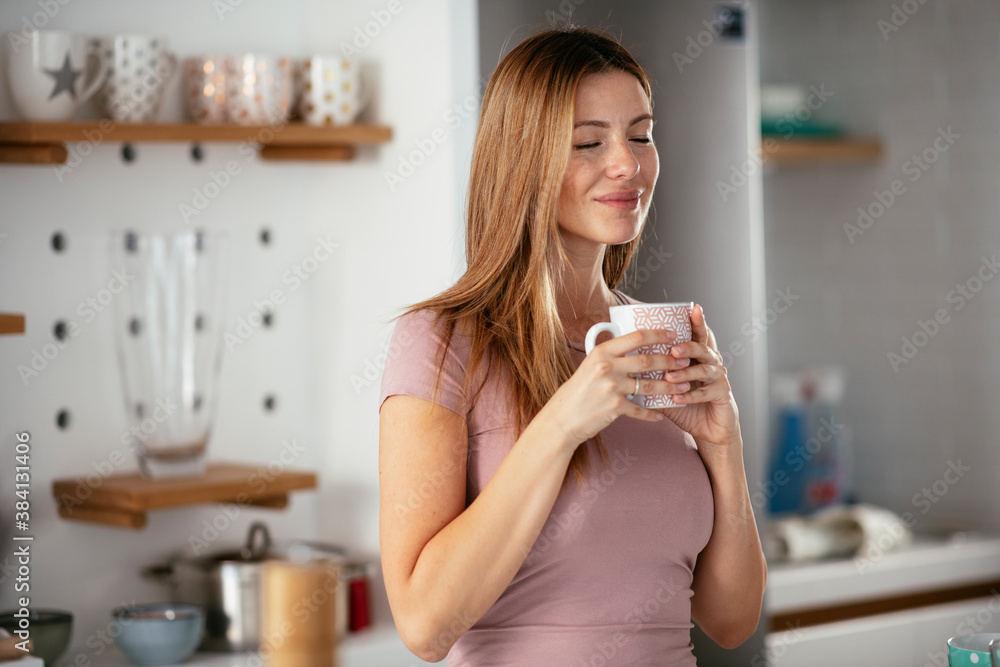 Young woman in kitchen. Beautiful woman preparing breakfast and drinking coffee Young woman in kitchen. Beautiful woman preparing breakfast and drinking coffee