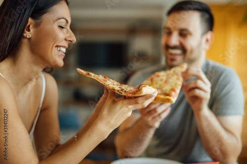 Close-up portrait of a smiling couple eating pizza for breakfast.