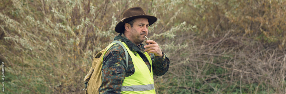 Fototapeta premium Duck hunter with shotgun walking through a meadow.