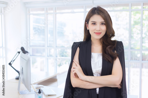 Asian confident working woman who has a long hair with a black suit is standing and arm crossing in work from home concept. Free Download Asian confident working woman who has a long hair with a black suit is standing and arm crossing in work from home concept. - GFXLoad