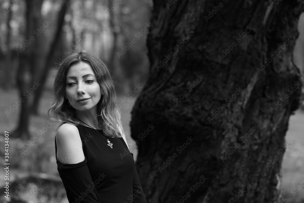 Woman near an old tree in the park in black and white Woman near an old tree in the park in black and white