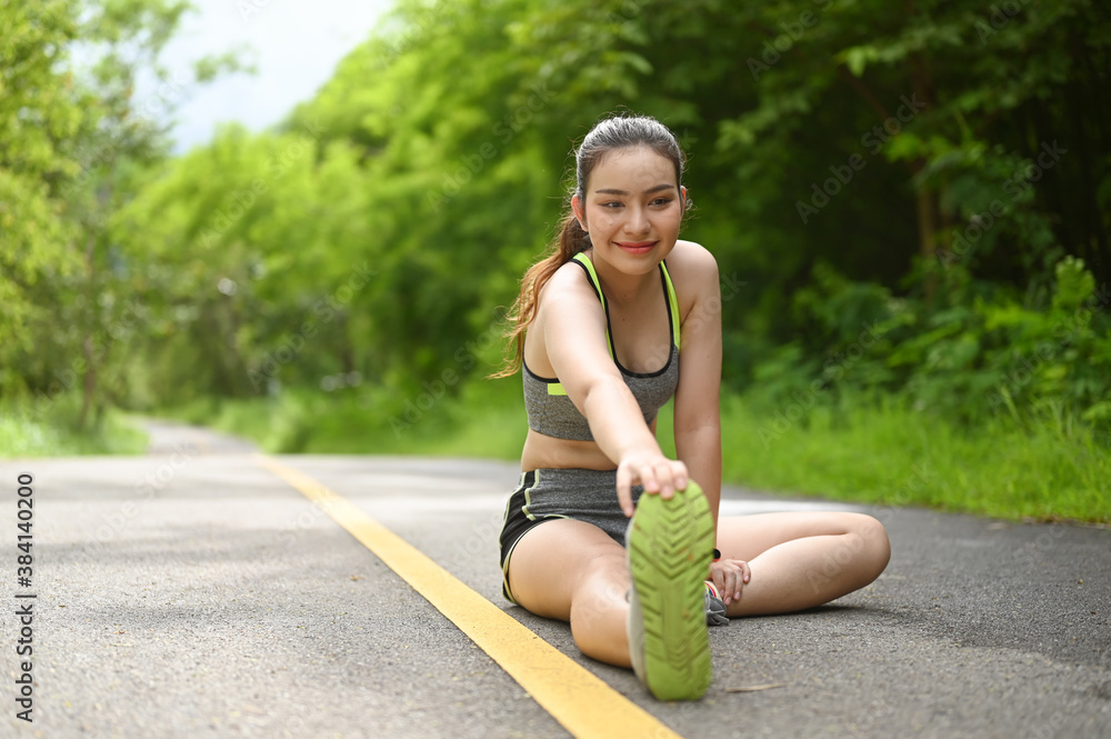Young woman warming up and stretching legs before jogging in the park. Young woman warming up and stretching legs before jogging in the park.