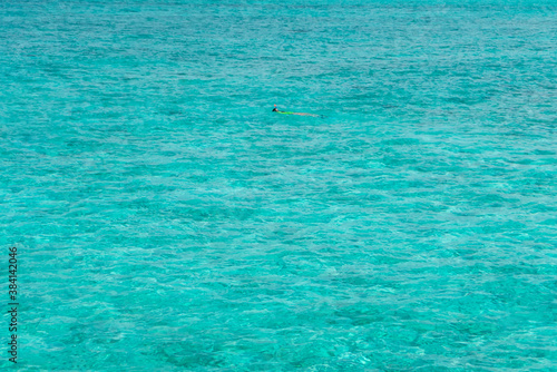 Girl in vivid color swim suit snorkeling alone isolated in waters of Indian ocean on Maldive islands