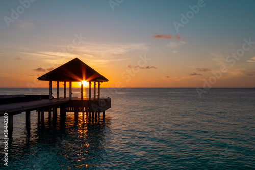 Sun light goes through building on water of Indian ocean during sun set on Maldive islands © ilyablinov