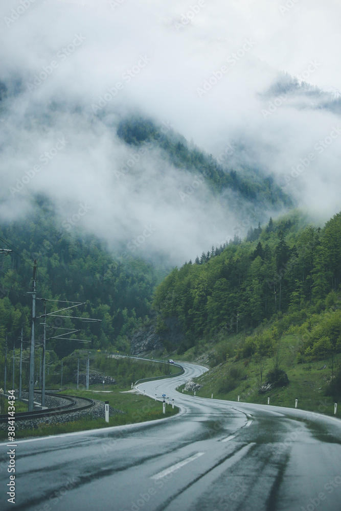 Amazing rainy landscape with winding road and cloudy mountain peaks. Austrian alps