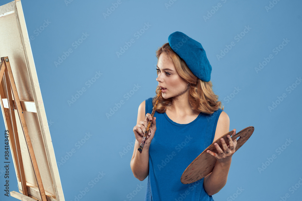 Woman artist blue beret drawing palette easel hobby creativity blue background