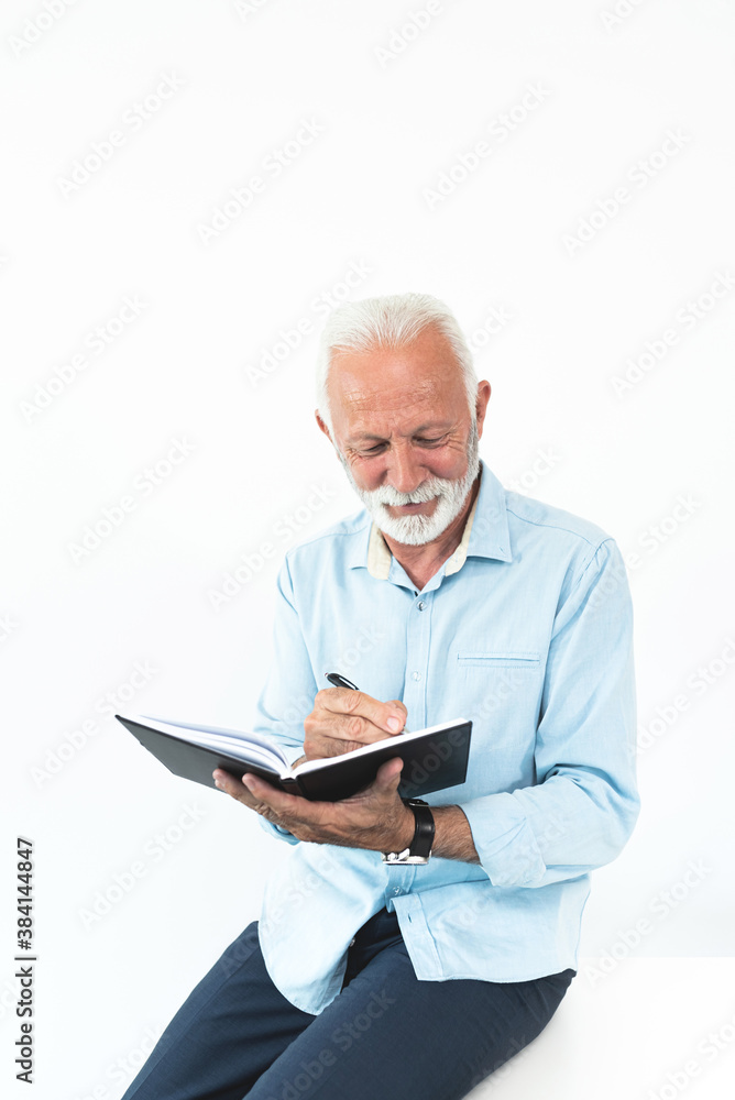 Smiling senior businessman writing notes in diary Smiling senior businessman writing notes in diary