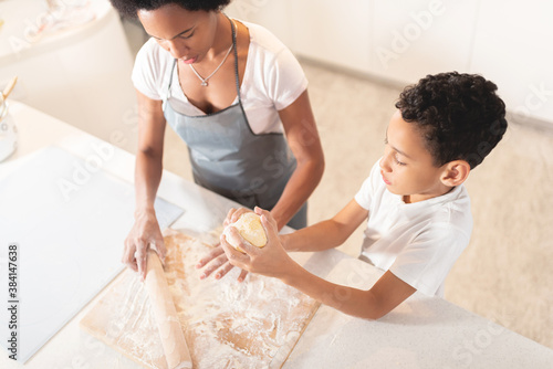 Boy and mother cooking in kitchen to make pizza