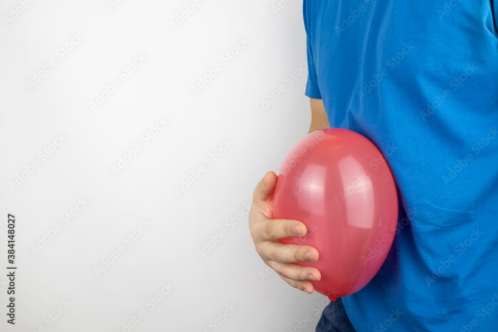 Bloating and flatulence concept. The man holds a red balloon near the abdomen, which symbolizes gas problems. Intestinal tract and digestive system Bloating and flatulence concept. The man holds a red balloon near the abdomen, which symbolizes gas problems. Intestinal tract and digestive system