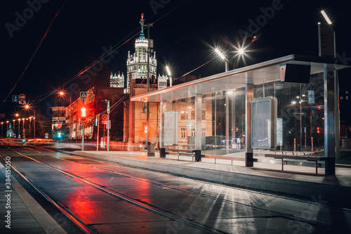A modern tram stop in the center of Moscow. Night. No people. Lanterns and city lights are on. A Stalinist skyscraper in the background
