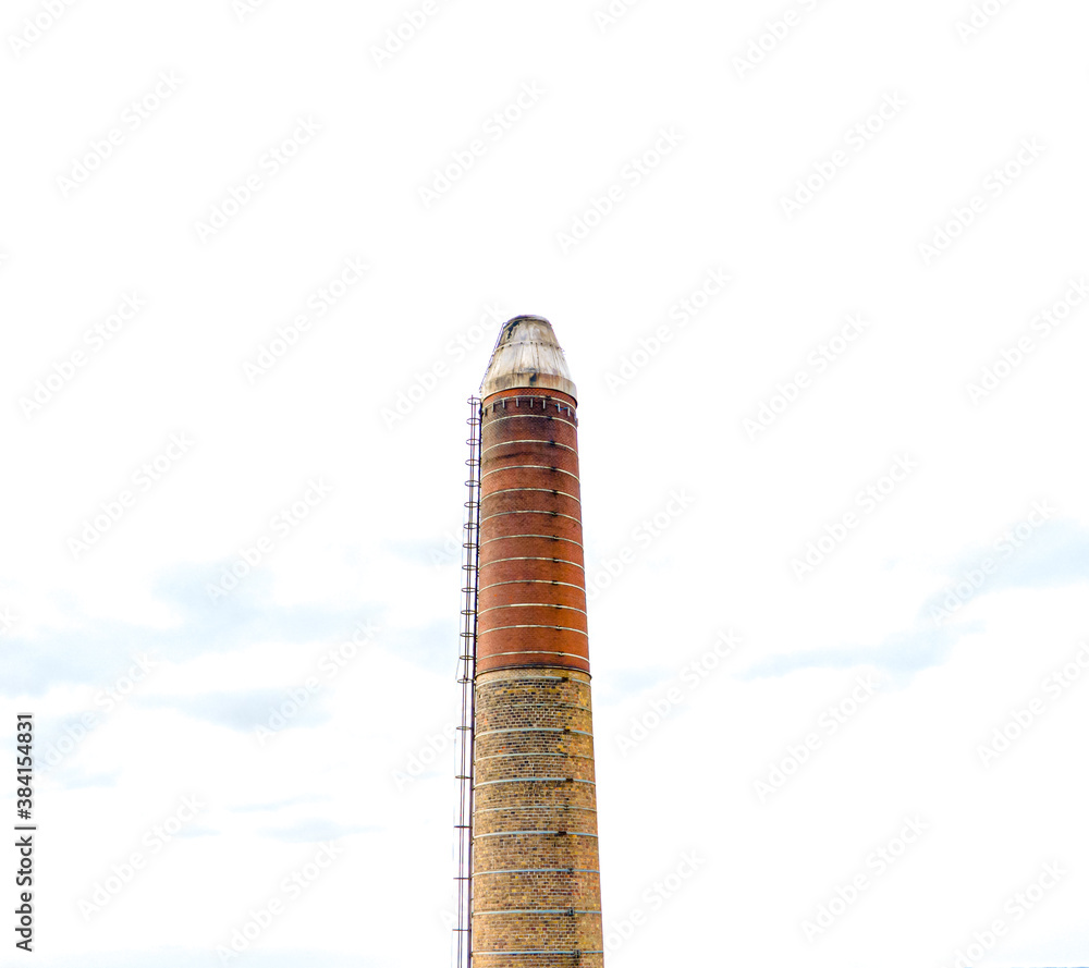 Large industrial brick chimney with a bright white sky in the background. 