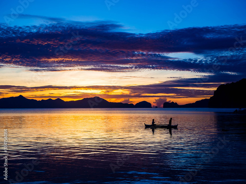Silhouette of people on a boat and vivid sunset over the ocean in El Nido, Philippines