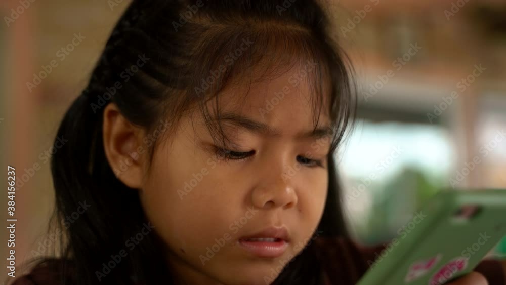 Little girl is looking at the smartphone. The child is playing on the smartphone Little girl is looking at the smartphone. The child is playing on the smartphone