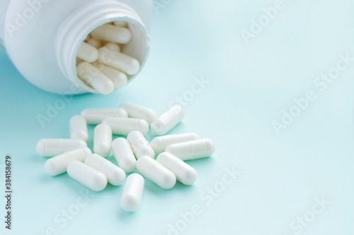  Medicine pills and bottle on blue background. Focus on pills. Copy space for text. Covid-19.