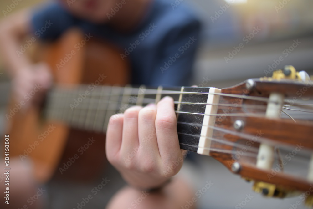 A young kid playing guitar outdoors