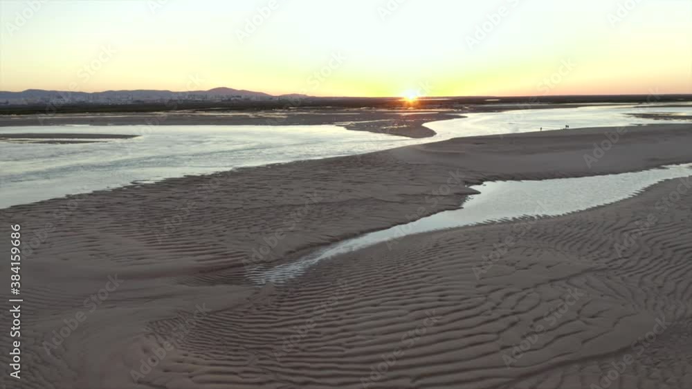 Sun burning on the horzion during sunset while drone flies backwards to reveal beautiful golden beach Sun burning on the horzion during sunset while drone flies backwards to reveal beautiful golden beach