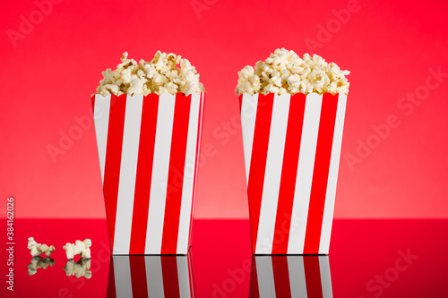 Red and white Popcorn box filled with popcorn on red background