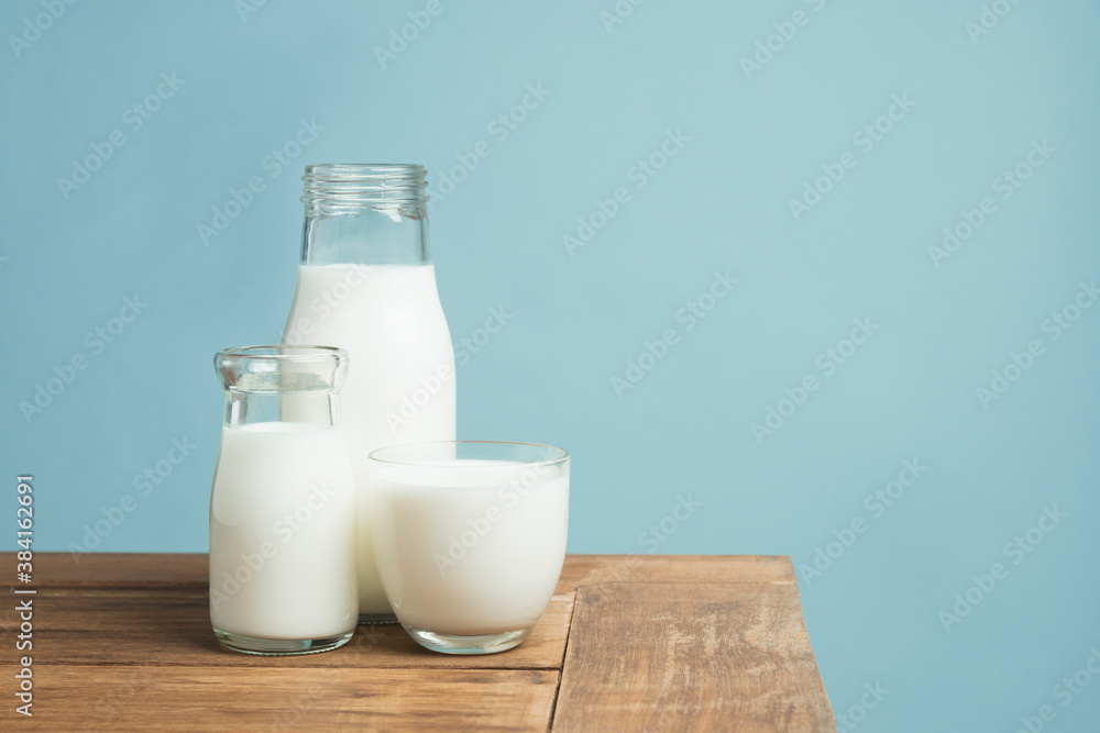 Bottles of fresh milk on wooden table on light blue background. Bottles of fresh milk on wooden table on light blue background.