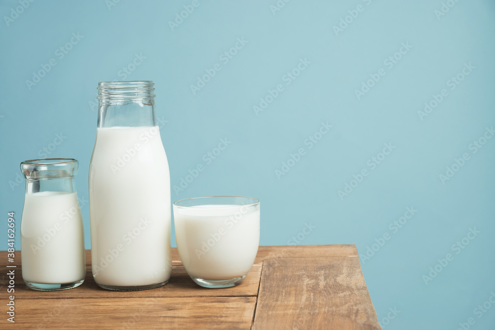 Bottles of fresh milk on wooden table on light blue background. Bottles of fresh milk on wooden table on light blue background.