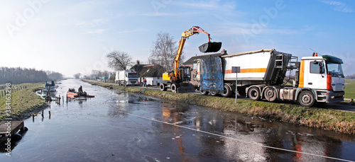 Dredging of inland canals in winter by pushboat and crane; the dredging spoil is deposited in a truck