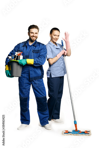 Attractive young woman and man in cleaning uniform and rubber gloves holding a broom cleaning products in his hands, isolated on white background.