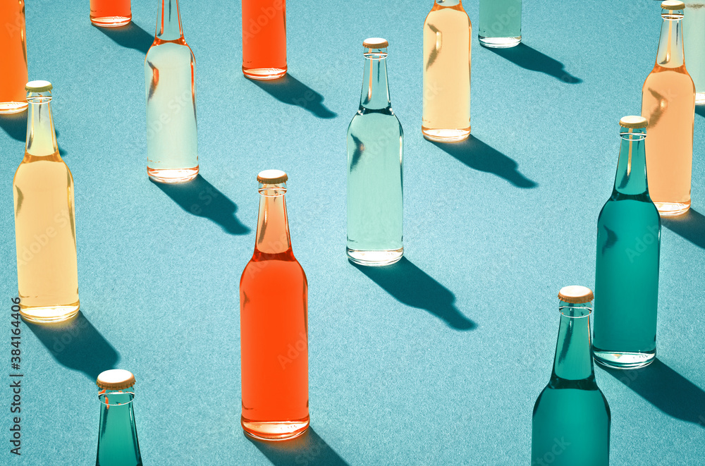 Various color glass bottles with shadows on blue surface. - obrazy, fototapety, plakaty 