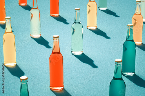 Various color glass bottles with shadows on blue surface.
