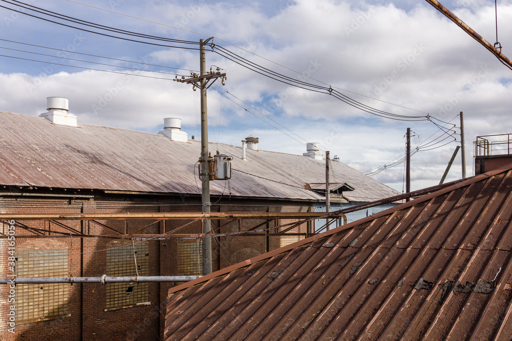 Tin rooftops of various buildings at an abandoned factory site with cloudy sky Tin rooftops of various buildings at an abandoned factory site with cloudy sky