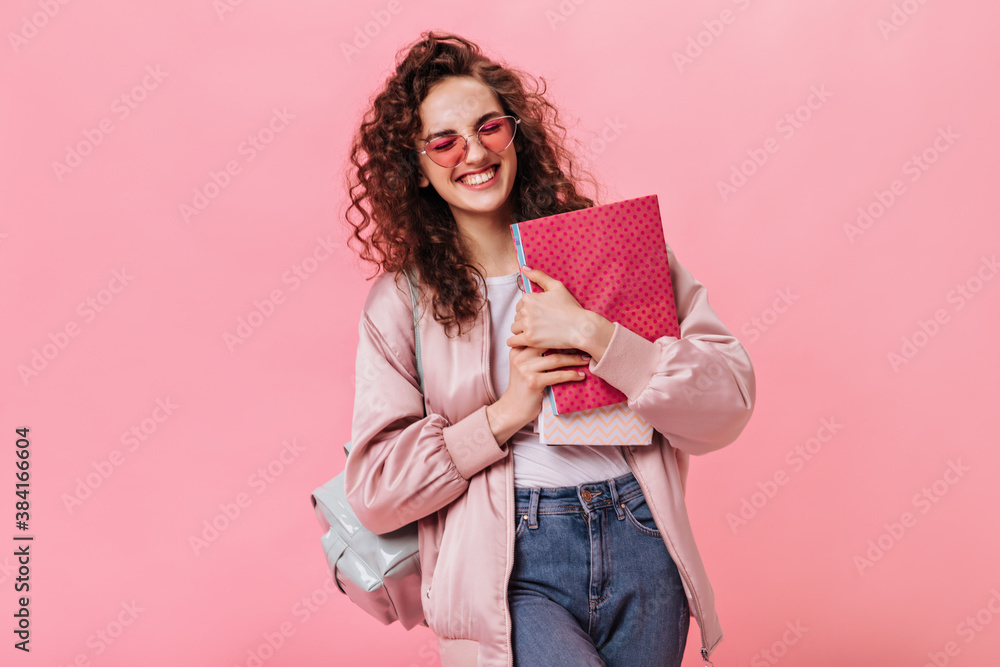Optimistic woman in silk jacket and jeans holding notebooks Optimistic woman in silk jacket and jeans holding notebooks