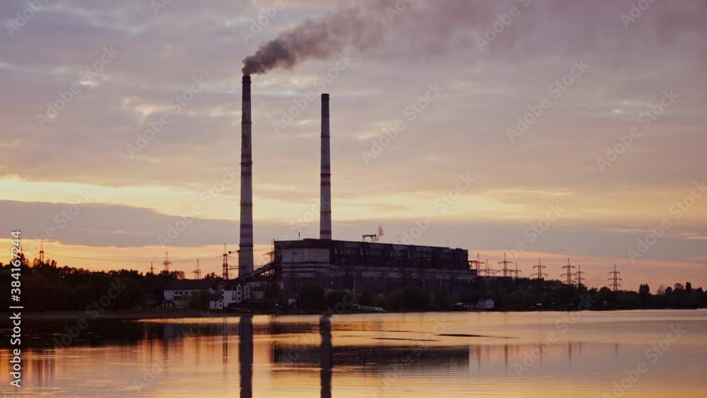 Factory near the river. Industrial plant with dirty smoke going from pipe at sunset. Harmful manufacturing in nature. Factory near the river. Industrial plant with dirty smoke going from pipe at sunset. Harmful manufacturing in nature.