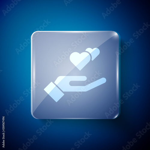 White Heart in hand icon isolated on blue background. Hand giving love symbol. Valentines day symbol. Square glass panels. Vector.