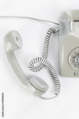 Studio photo of gray vintage rotary telephone in bright setting.