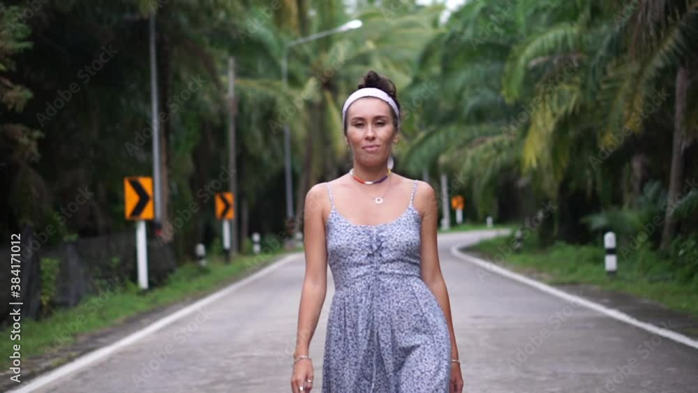 Beautiful girl walking along the palm road and hitchhiking and dances Beautiful girl walking along the palm road and hitchhiking and dances