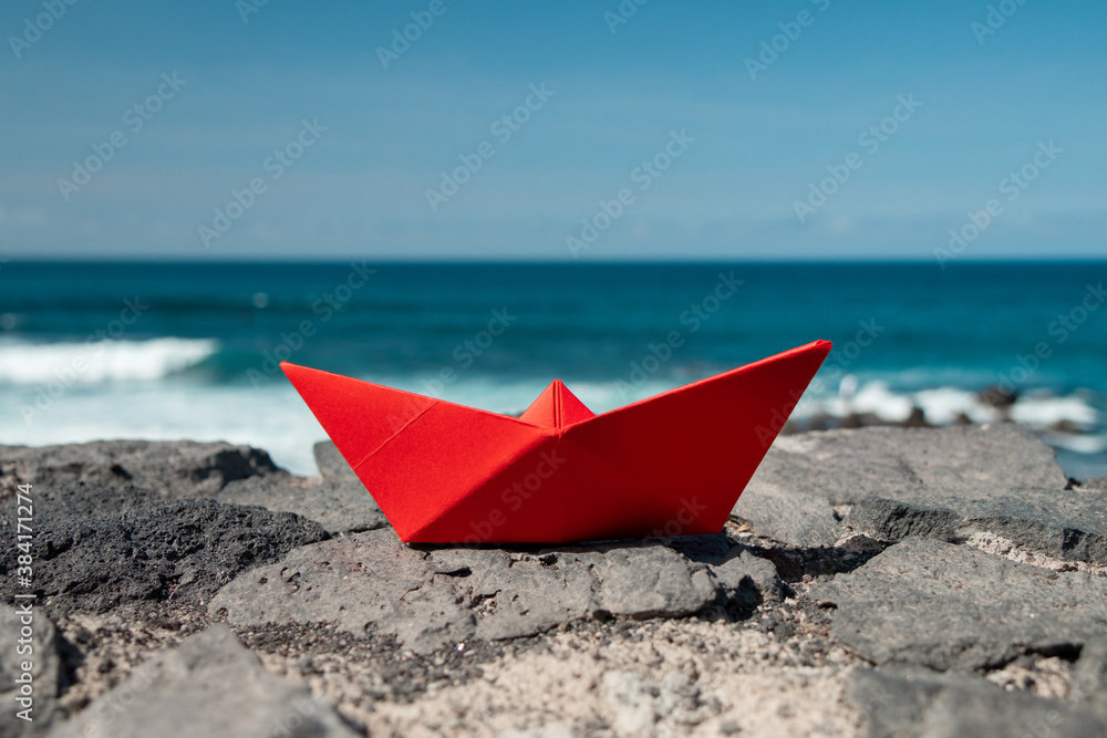 Red paper boat in front of the ocean outdoors Red paper boat in front of the ocean outdoors