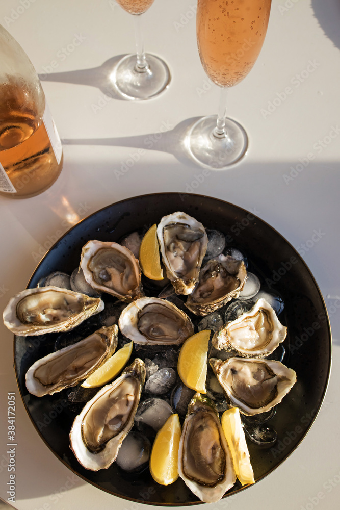 Fototapeta premium Oysters with lemon and two glasses of rose sparkling wine.