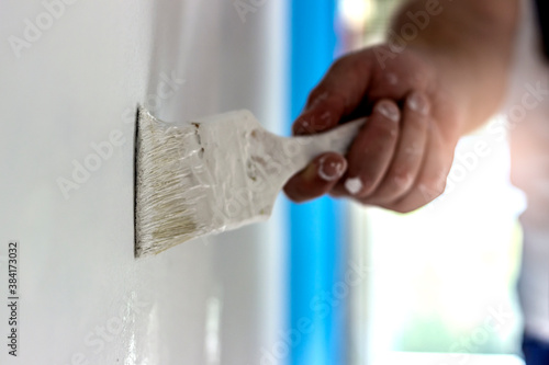 Wallpaper Mural Shot of a young man painting a blue wall with a brush. Bearded painter painting apartment interior. Male hand painting the wall with white paint brush. Painting apartment,renovating with white color Torontodigital.ca