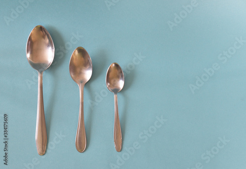 Three spoons of different sizes laid out in a row on a light blue background.