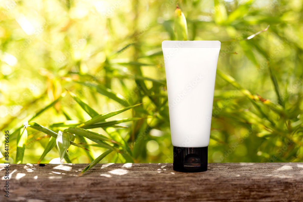 Cosmetic bottle container with green leaves, on the green background. Blank label package for branding mock up. Natural organic beauty product concept. White tube, skincare, healthcare. Sunny forest. Cosmetic bottle container with green leaves, on the green background. Blank label package for branding mock up. Natural organic beauty product concept. White tube, skincare, healthcare. Sunny forest.