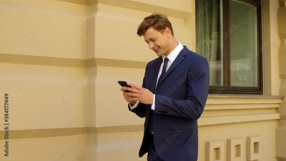 Cheerful businessman using mobile phone outdoors. Happy professional Cheerful businessman using mobile phone outdoors. Happy professional