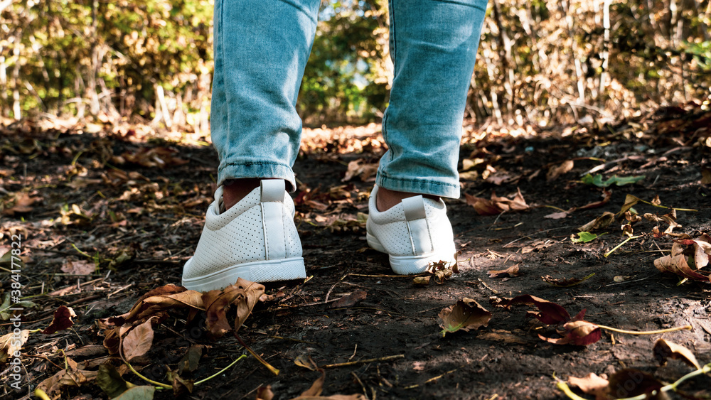 Female legs in jeans and white sneakers Female legs in jeans and white sneakers