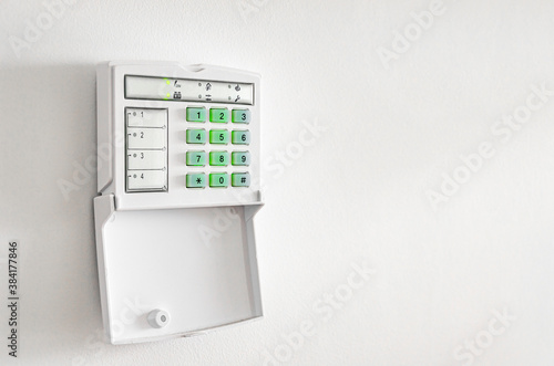 Electronic control panel of the apartment and office security alarm system with electronic keypad on a white wall