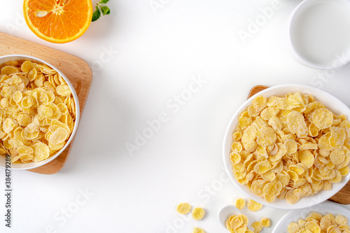 Top view of corn flakes bowl with milk on white background.