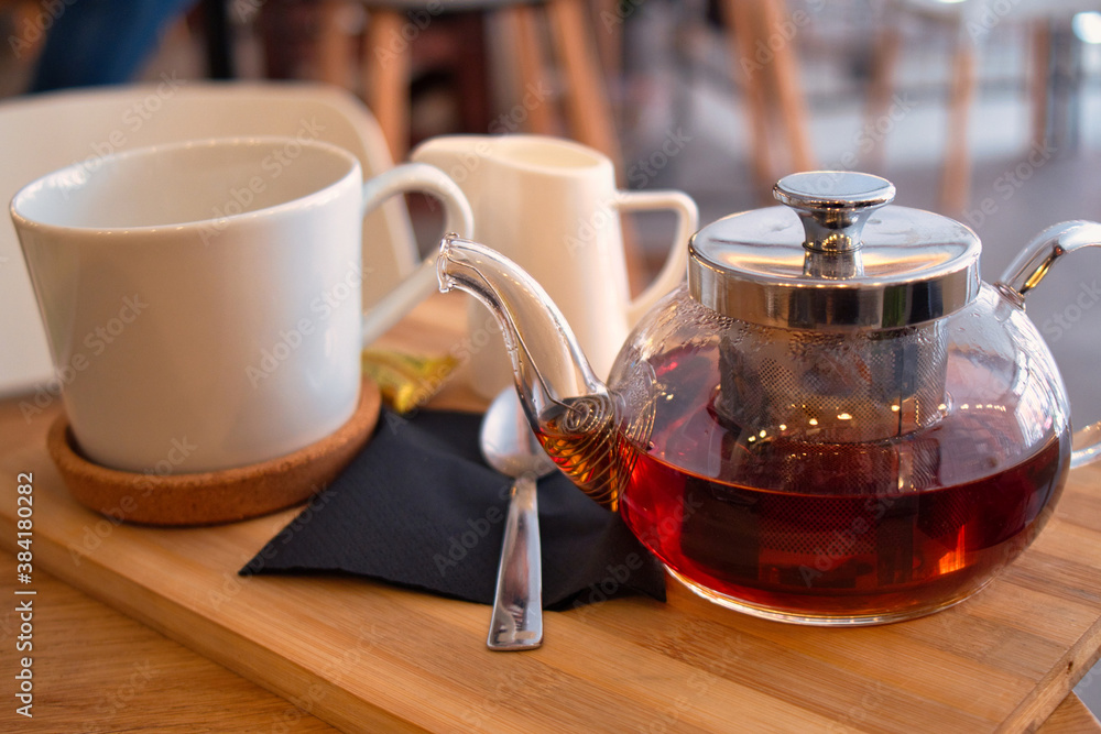 Glass pot and cup of delicious black tea for autumn day Glass pot and cup of delicious black tea for autumn day