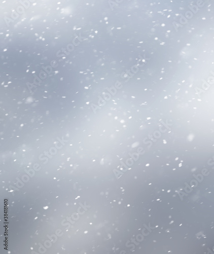 White snowflakes on a gray blurred inhomogeneous background, winter abstract background