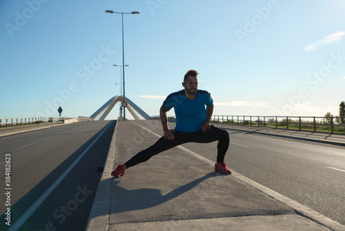 Runner doing body stretches to start his morning training. © Gusta Cabrera