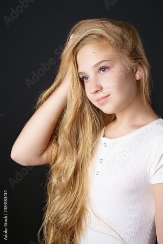 a girl with long blonde hair poses for the camera on a black background.