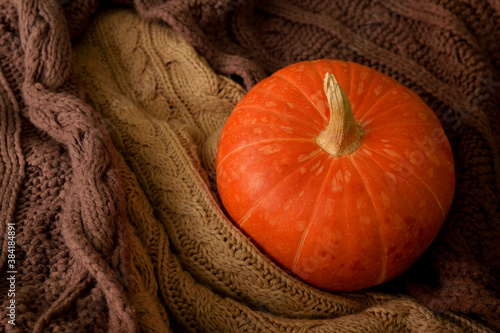 An orange pumpkin sits on two scarves. 