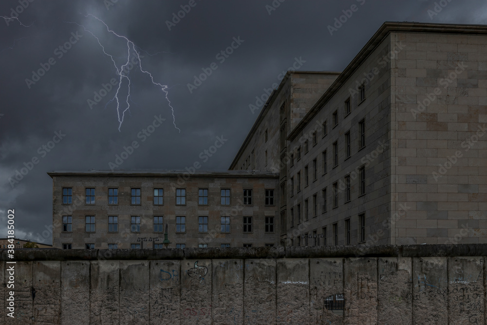 Berlin Wall dark ominous sky with lightning Detlev-Rohweddar Haus in background nobody