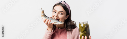 panoramic shot of woman with open mouth holding jar with pickled cucumbers and dried fish isolated on white © LIGHTFIELD STUDIOS