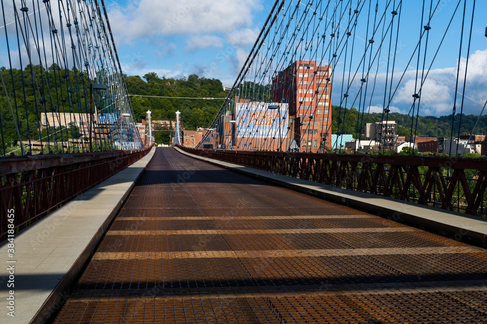 Φωτογραφία This is a wide view showing the cables and metal grate deck of the historic Wheeling Suspension Bridge that carries the National Road over the Ohio River in Wheeling, West Virginia